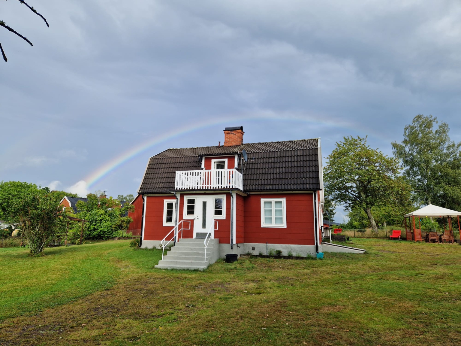 Das rote Schreibzeit-Haus unter einem Regenbogen